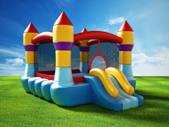 Bounce house standing on green grass. 3D illustration.